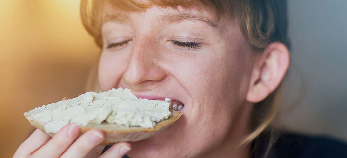 Woman eating a slice of bread with spread