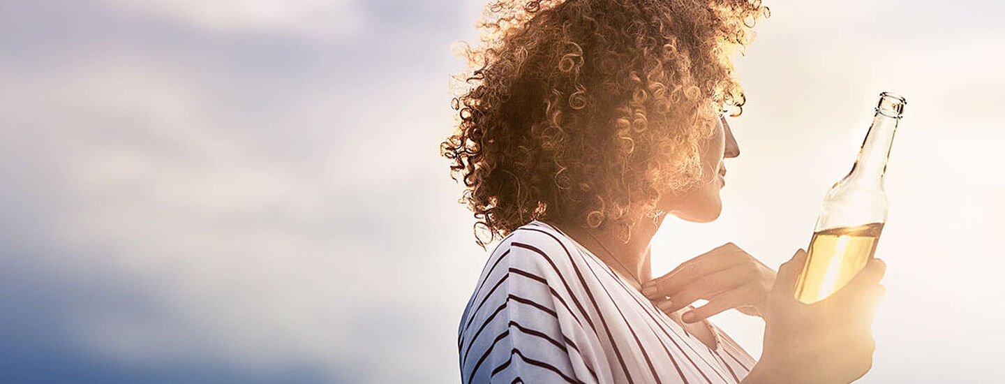 Woman holding a bottle of lemonade and looking into the distance