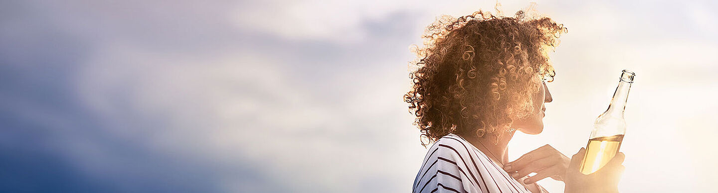 Woman holding a bottle of lemonade and looking into the distance