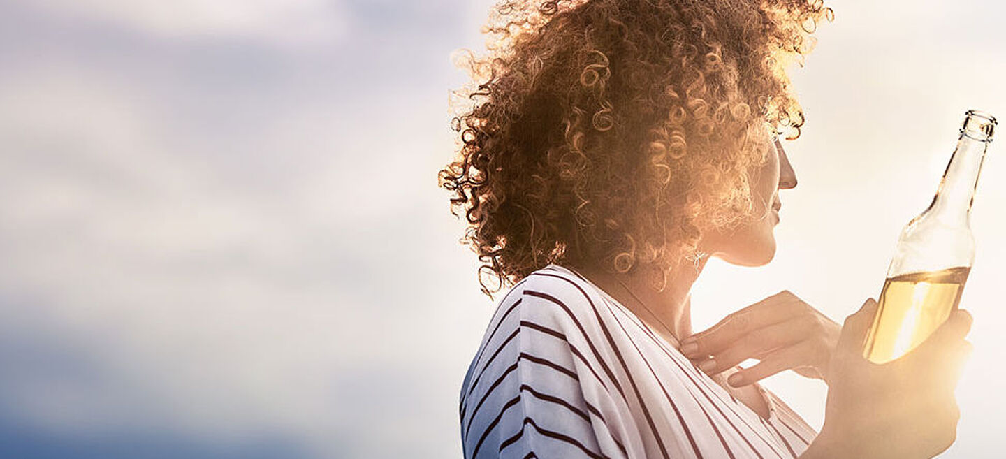 Woman holding a bottle of lemonade and looking into the distance