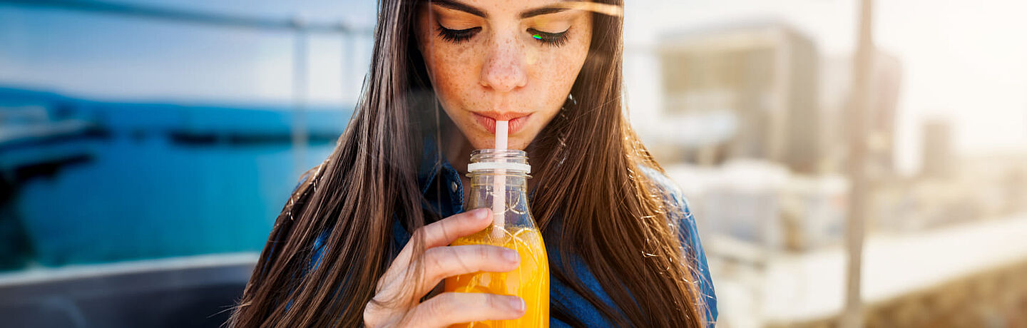 menina a beber suco de laranja