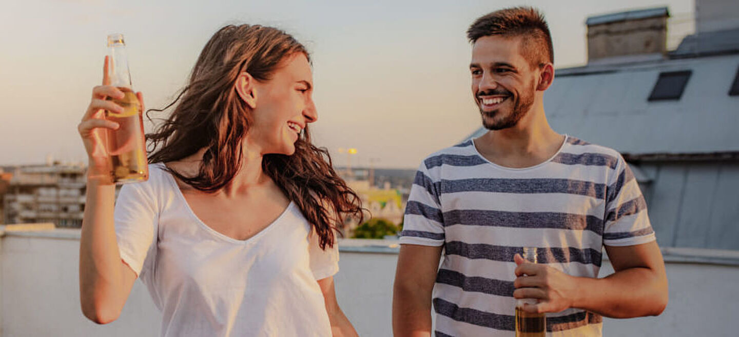 Eine Frau und ein Mann trinken alkoholische Getränke auf dem Balkon