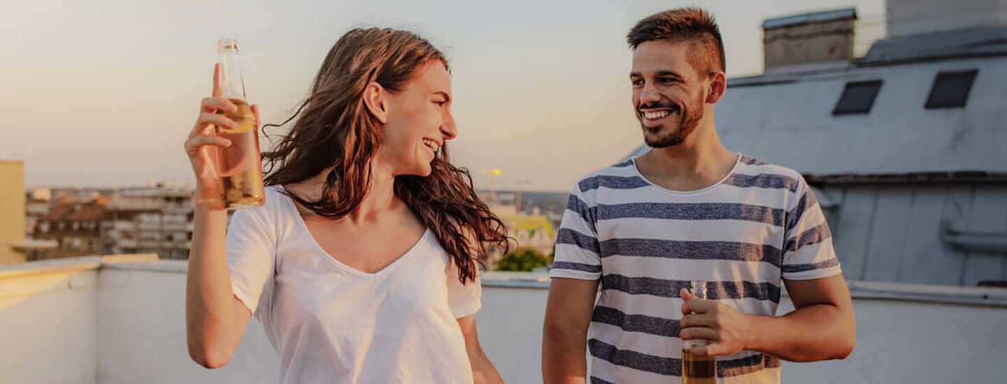 Eine Frau und ein Mann trinken alkoholische Getränke auf dem Balkon