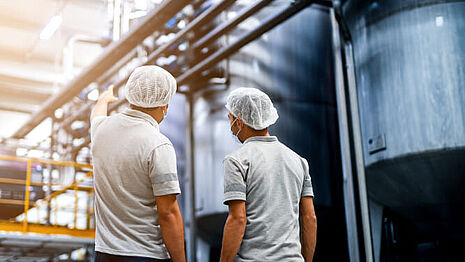 Men in hair nets are at the production site