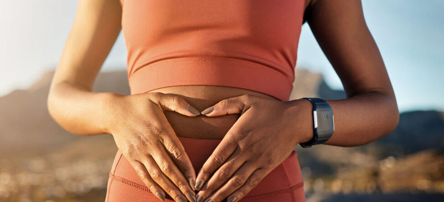 Frau mit herzförmigen Händen auf ihrem Bauch