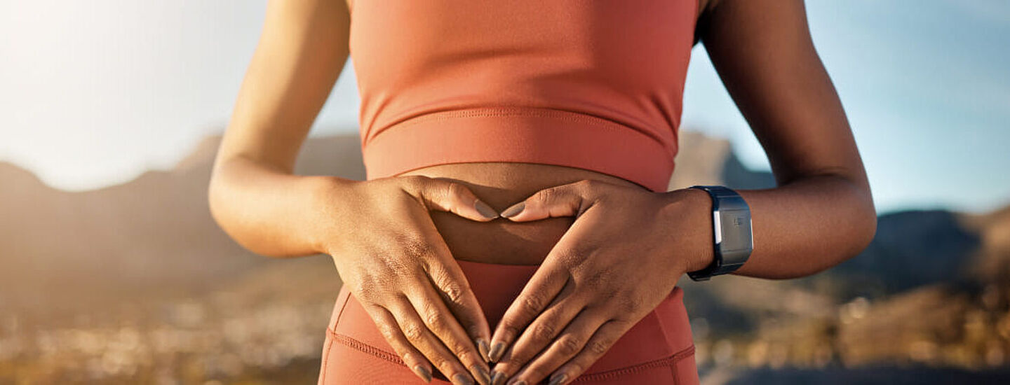 Frau mit herzförmigen Händen auf ihrem Bauch