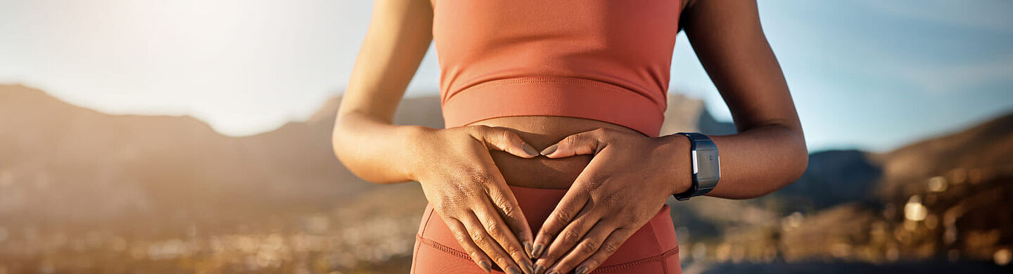 Frau mit herzförmigen Händen auf ihrem Bauch