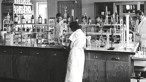 Old picture of people in robes working in the laboratory