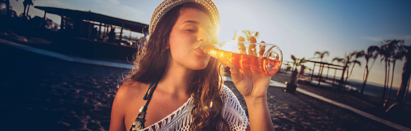 mulher a beber da garrafa um liquido vermelho