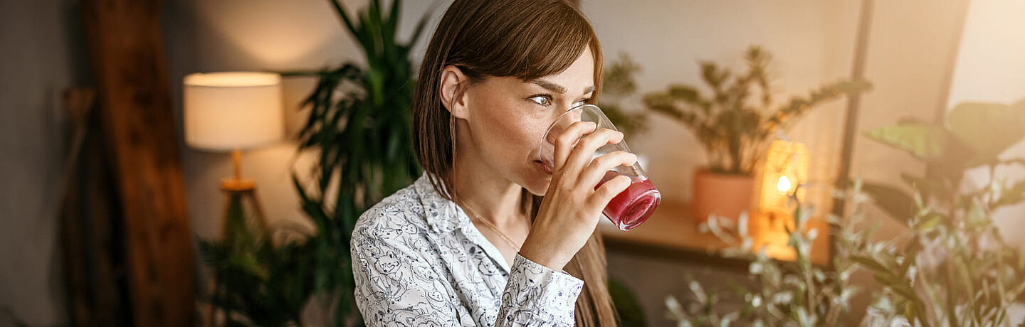 Frau trinkt rosafarbenen Saft