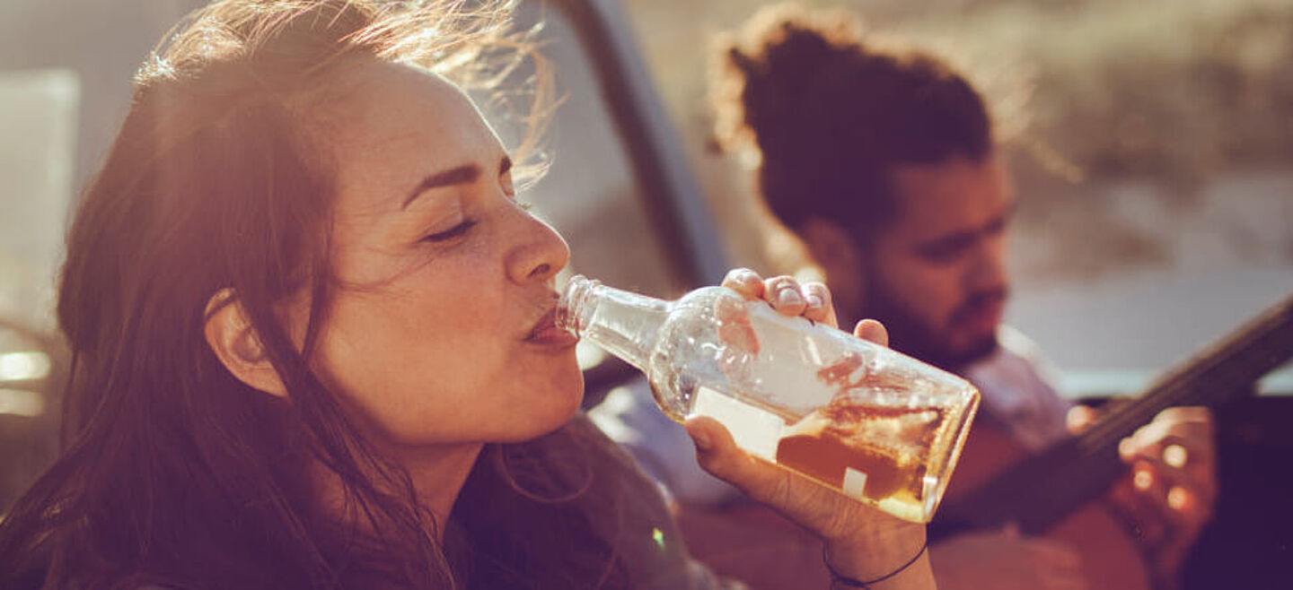 Eine Frau trinkt eine Flasche Biere