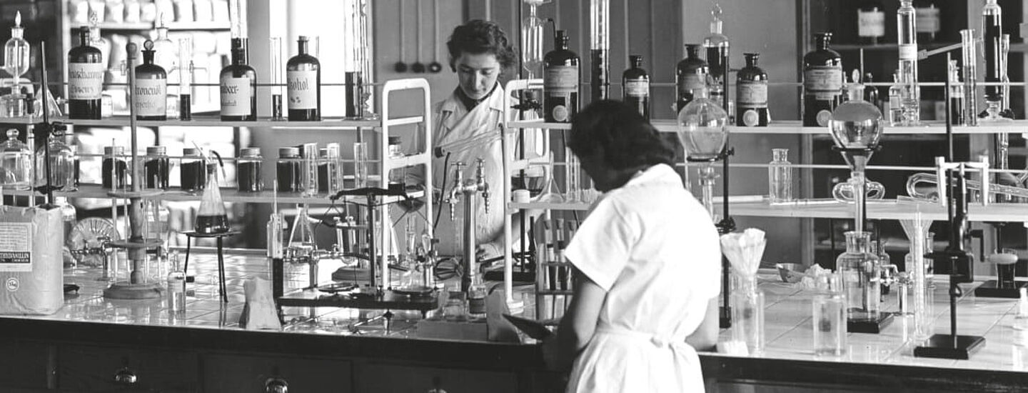 Antiga foto de pessoas em batas trabalhando no laboratório