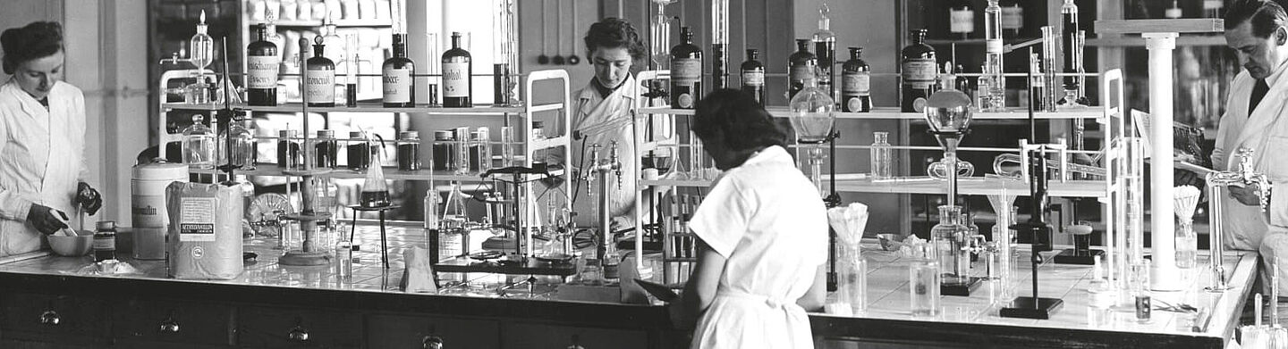 Antiga foto de pessoas em batas trabalhando no laboratório