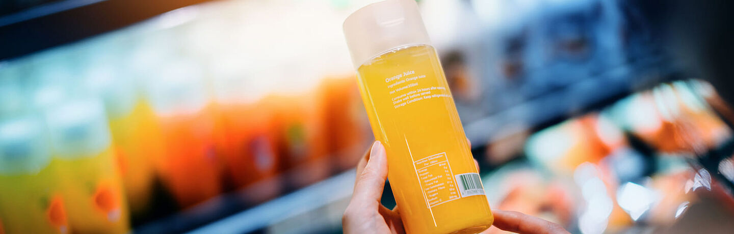 woman in the supermarket holding orange juice