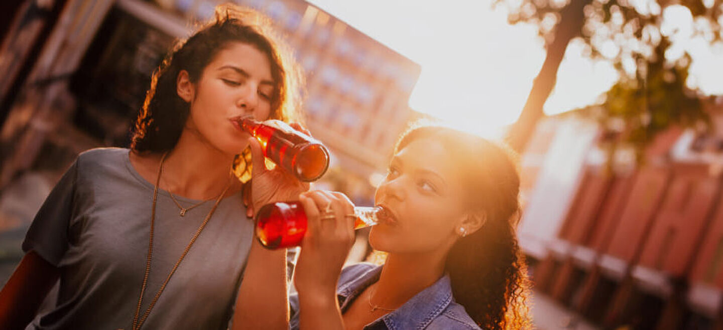 amigas a beber liquido vermelho de uma garrafa