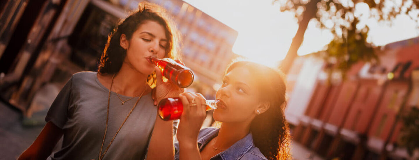 amigas a beber liquido vermelho de uma garrafa