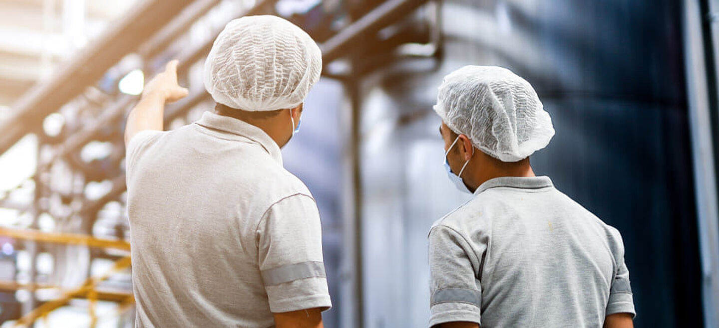 Men in hair nets are at the production site