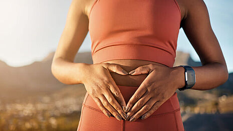 woman with hands on belly in the shape of a heart