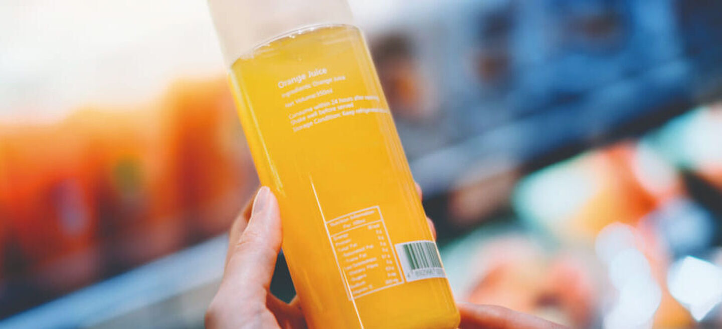 Frauen halten eine Flasche mit orangefarbener Flüssigkeit