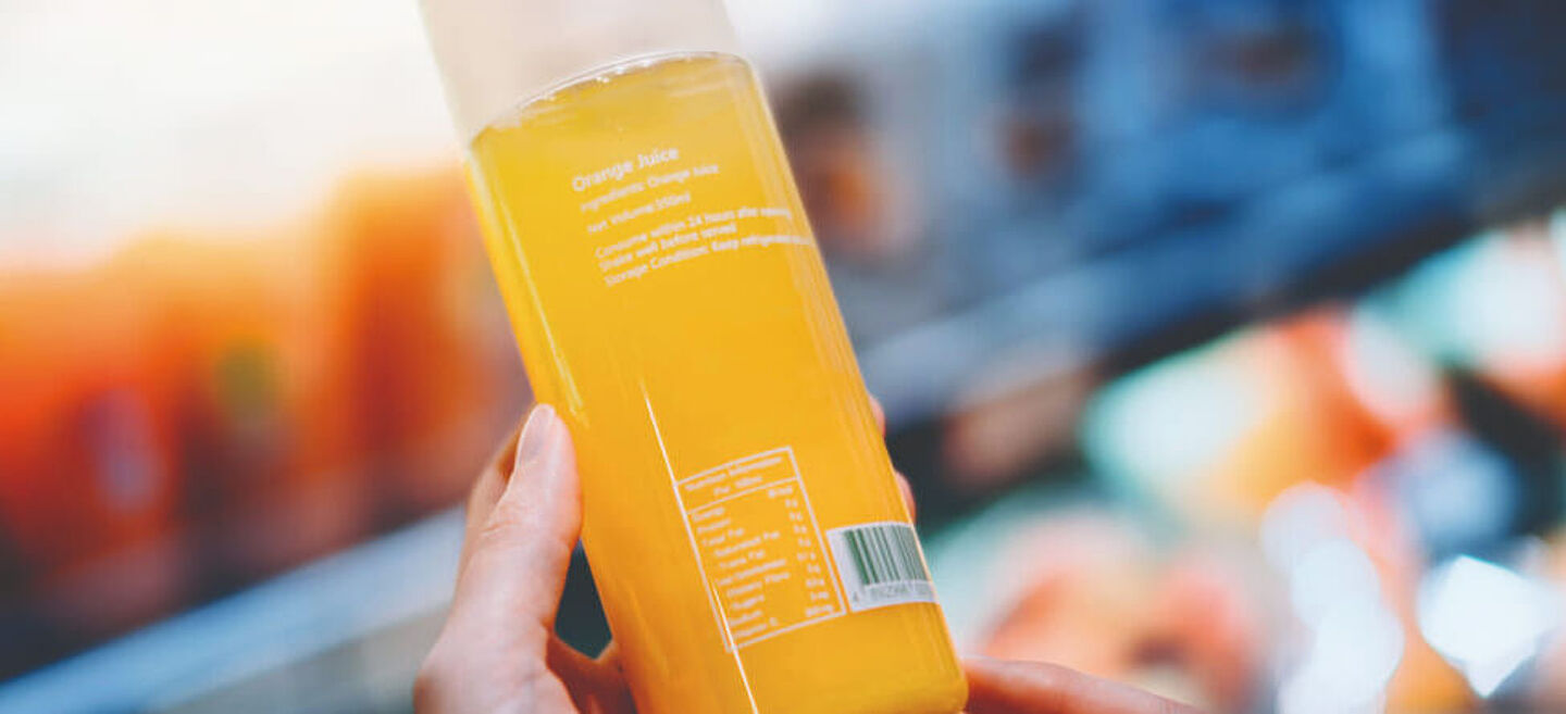 mujer sosteniendo una botella con líquido naranja